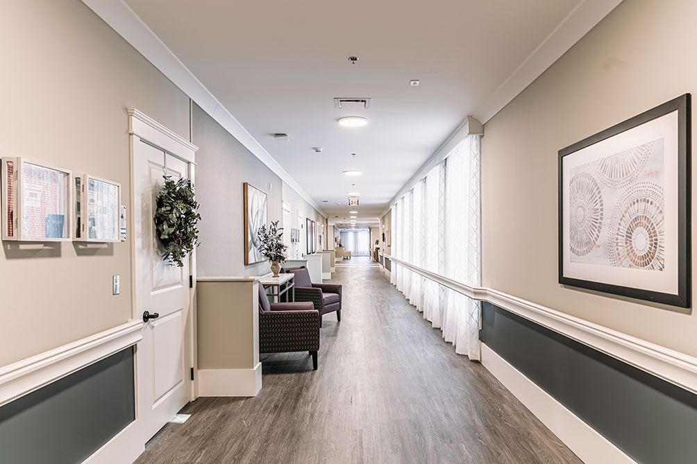 A modern hallway with seating and decor, featuring large windows and soft lighting.