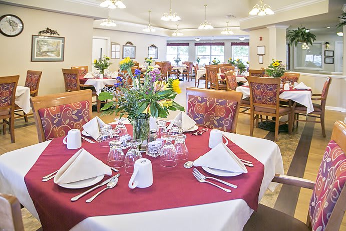 A well-decorated dining room with elegantly set tables, featuring floral centerpieces.