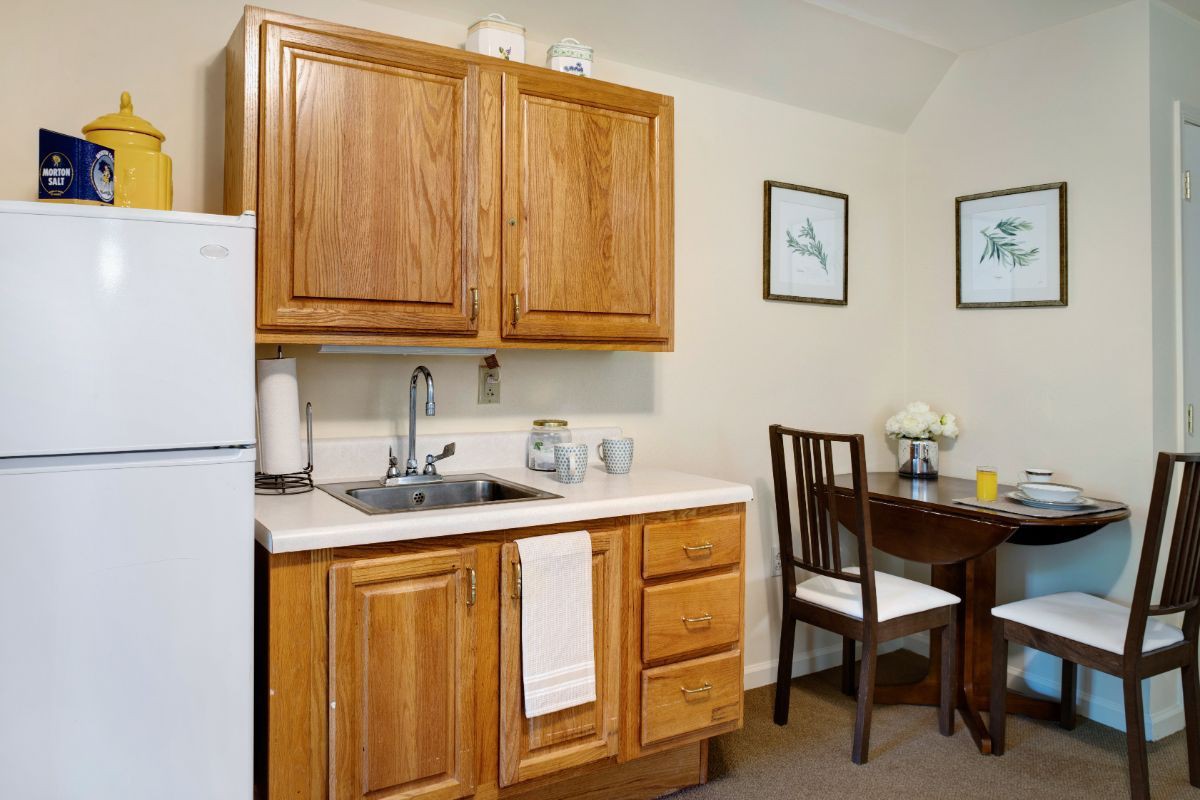 A cozy kitchen with wooden cabinets, a small dining area, and minimalist decor.
