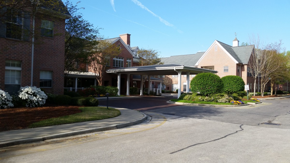 An outdoor view of a building entrance with a covered driveway and landscaped surroundings.