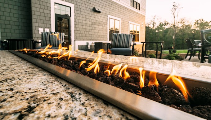 A cozy outdoor patio featuring a modern fire pit with comfortable seating.