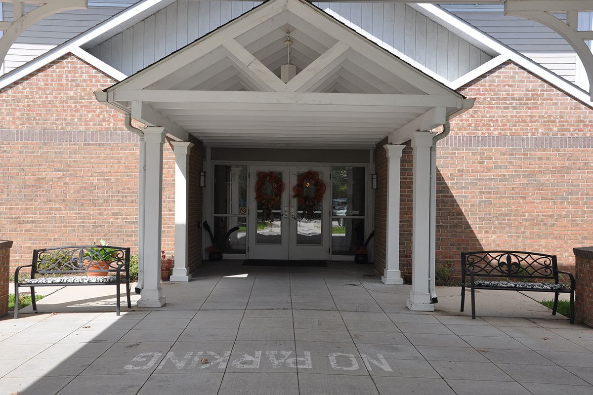 A covered entrance with columns leading to a building, displaying 'No Parking' on the pavement.