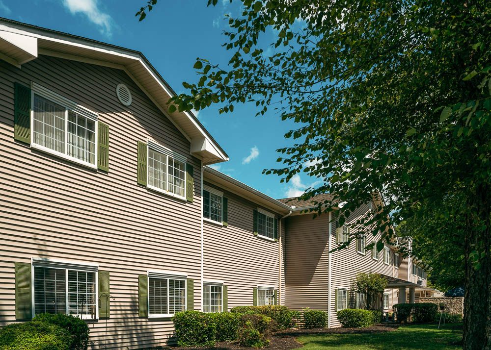 A suburban residential apartment building with trees and a clear blue sky.