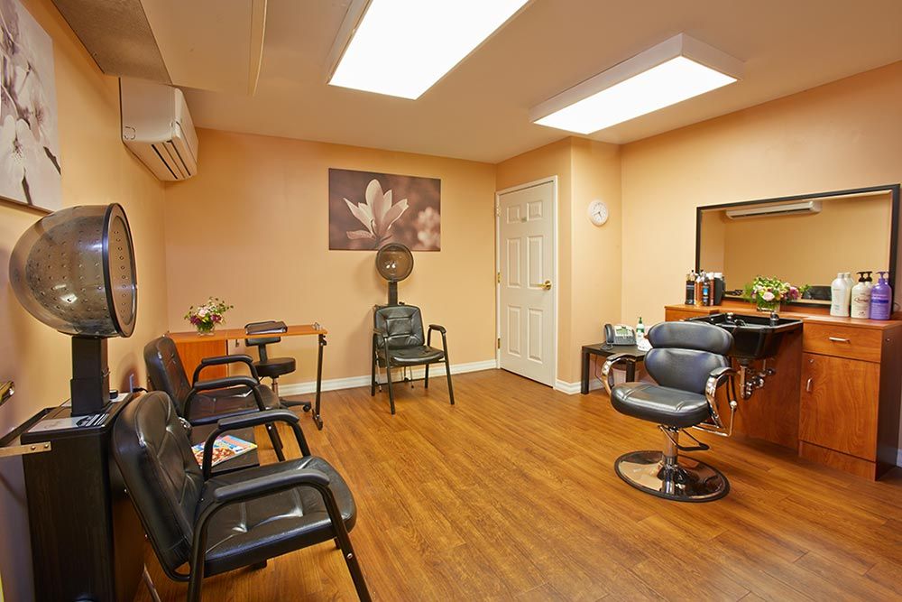 A cozy salon interior featuring a waiting area with chairs and a styling station.