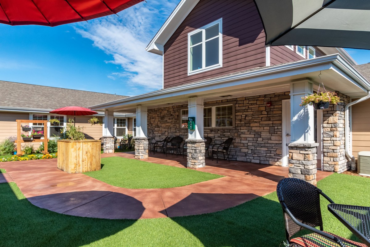 A sunny backyard with a well-maintained lawn and a cozy patio area for outdoor seating.