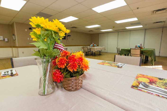 A meeting room features tables decorated with vases of sunflowers and baskets of red flowers.