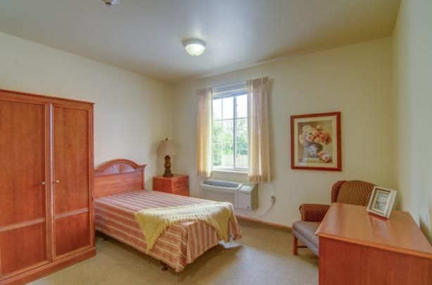 A simple bedroom with a single bed, furniture, and natural light from a window.