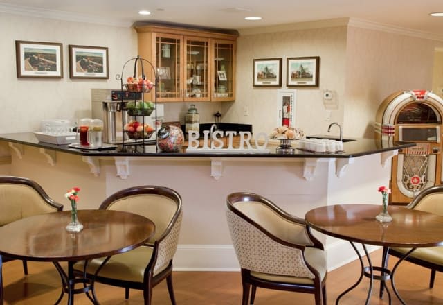A cozy kitchen and dining area with a counter, chairs, and tables, elegantly decorated.