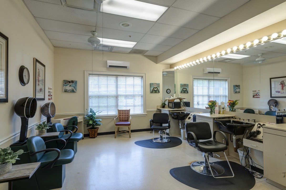A well-lit hair salon interior with chairs, mirrors, and windows.