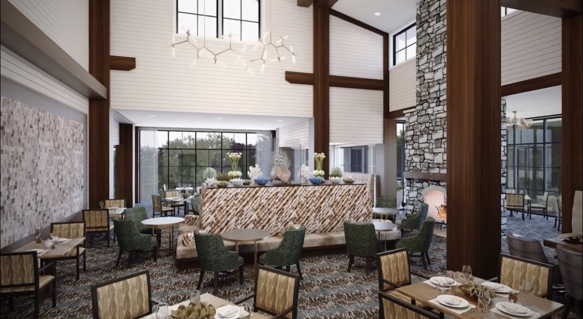 A modern lobby with comfortable seating and a high ceiling, featuring large windows and a stylish chandelier.