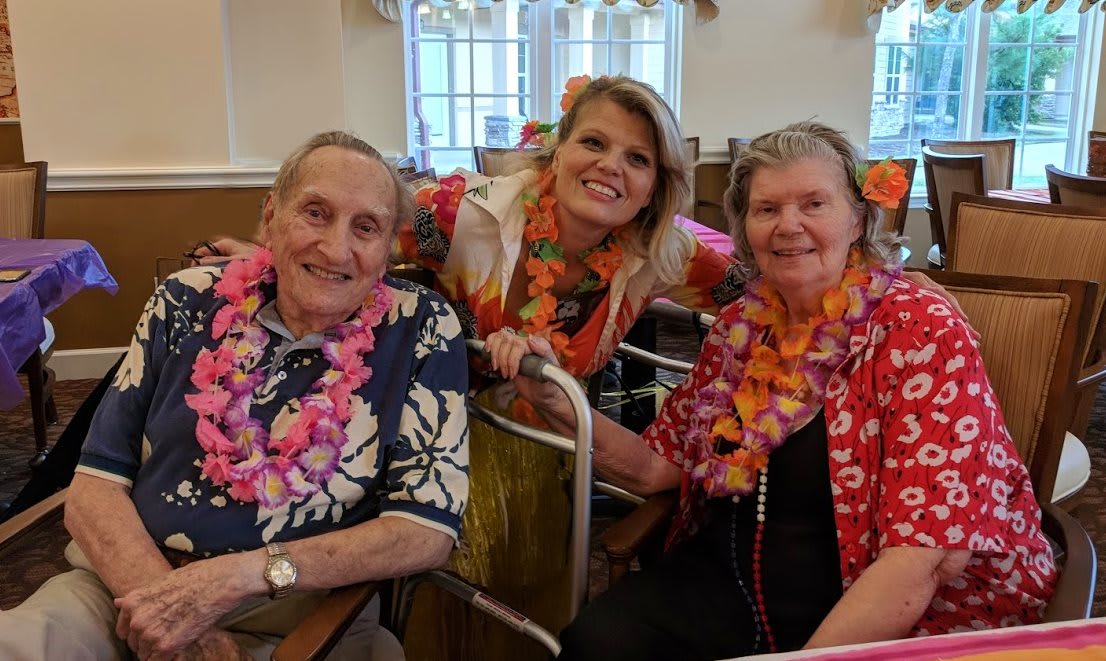 A joyful celebration with three people wearing colorful Hawaiian shirts and leis.