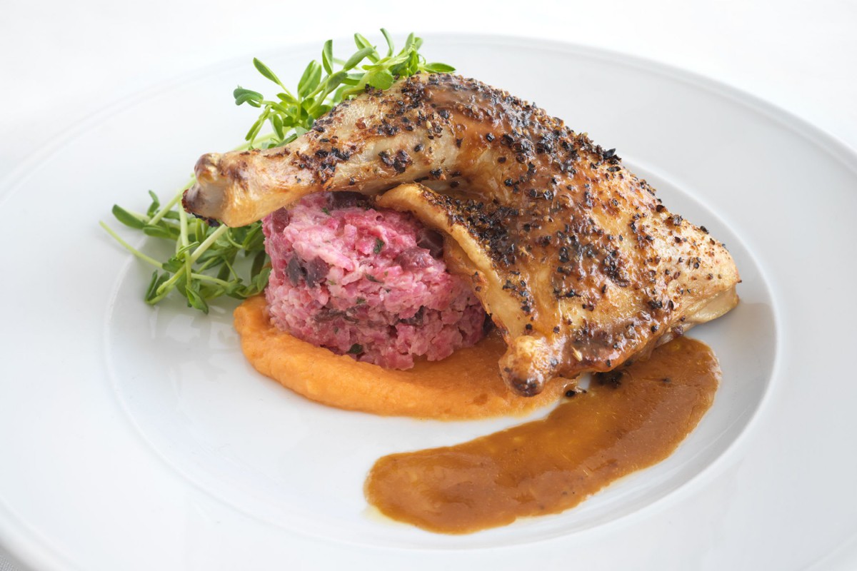 A beautifully plated gourmet dish featuring seasoned chicken, beet salad, and a rich sauce.