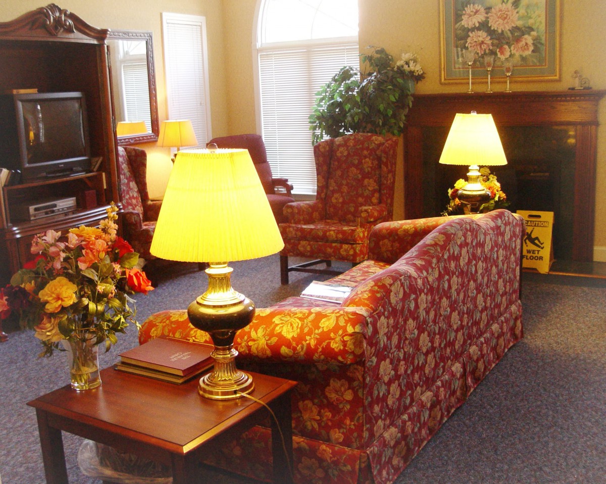 A cozy living room with traditional decor featuring sofas, lamps, and a coffee table with flowers.
