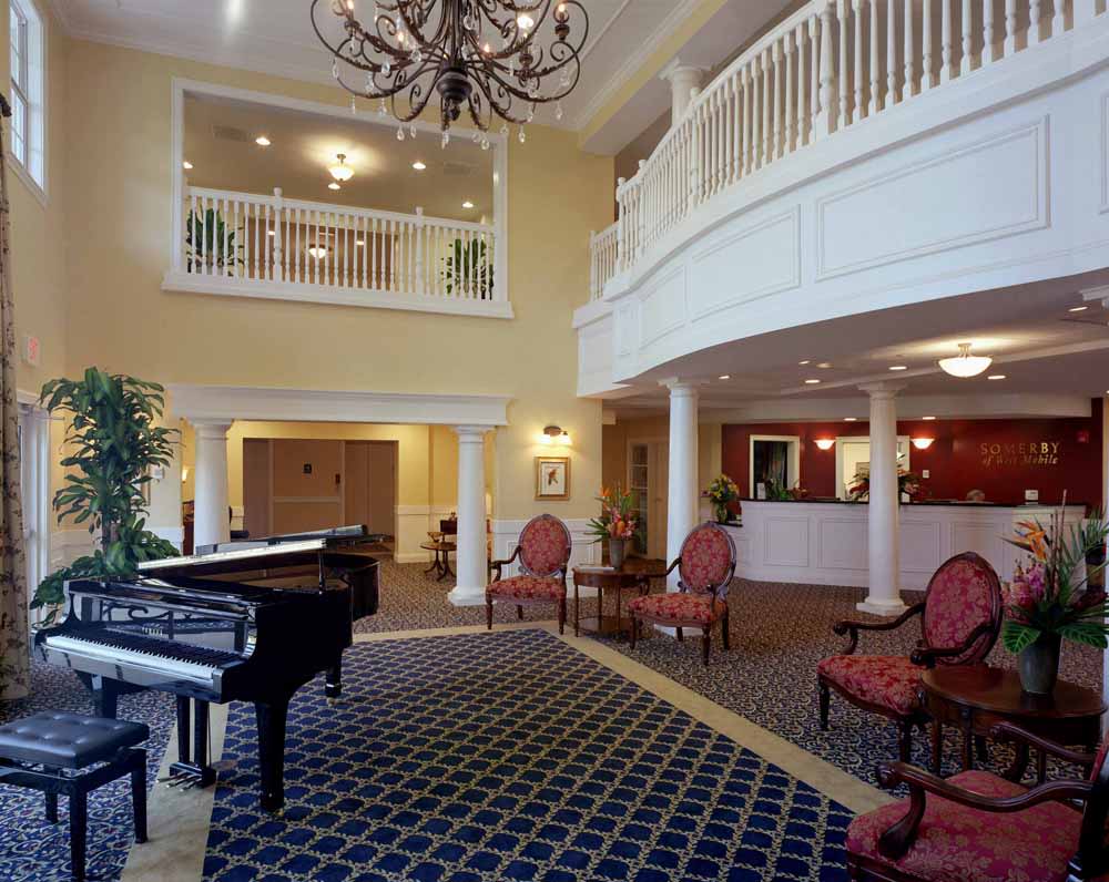 A spacious hotel lobby featuring a grand piano and elegant seating area under a chandelier.