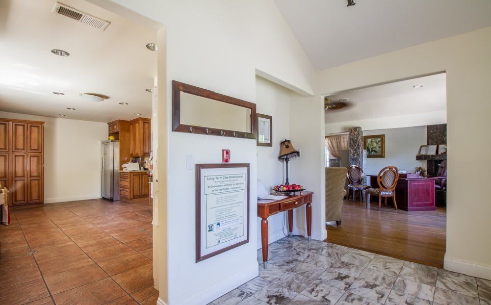 A spacious interior featuring a hallway with adjacent views of a kitchen and dining room, adorned with decorative furniture and wall art.