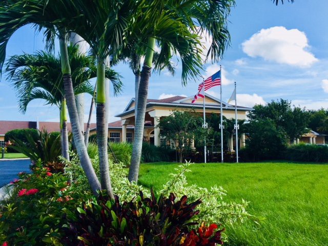 A picturesque view of a building with palm trees and an American flag on a sunny day.
