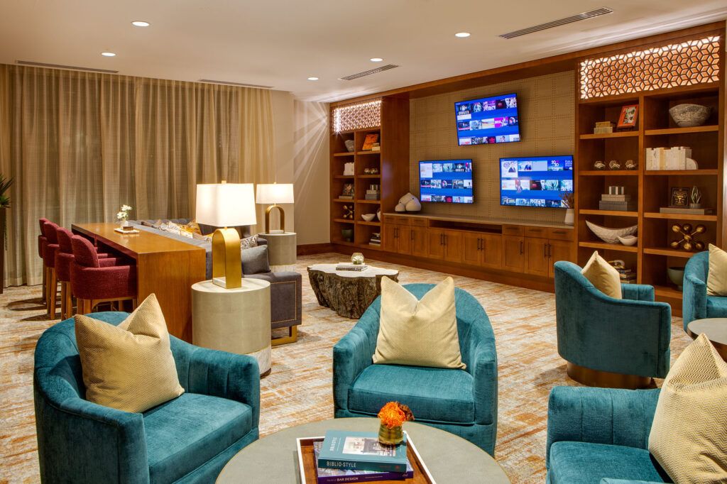 A modern living room with plush blue chairs, a large television display, and a cozy reading area.