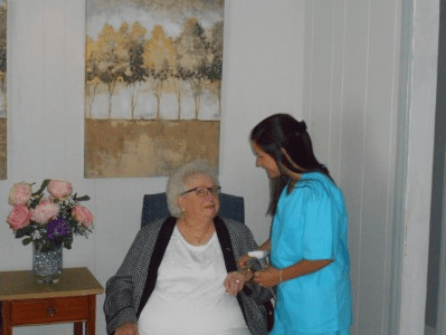 A nurse attends to an elderly woman in a healthcare setting.