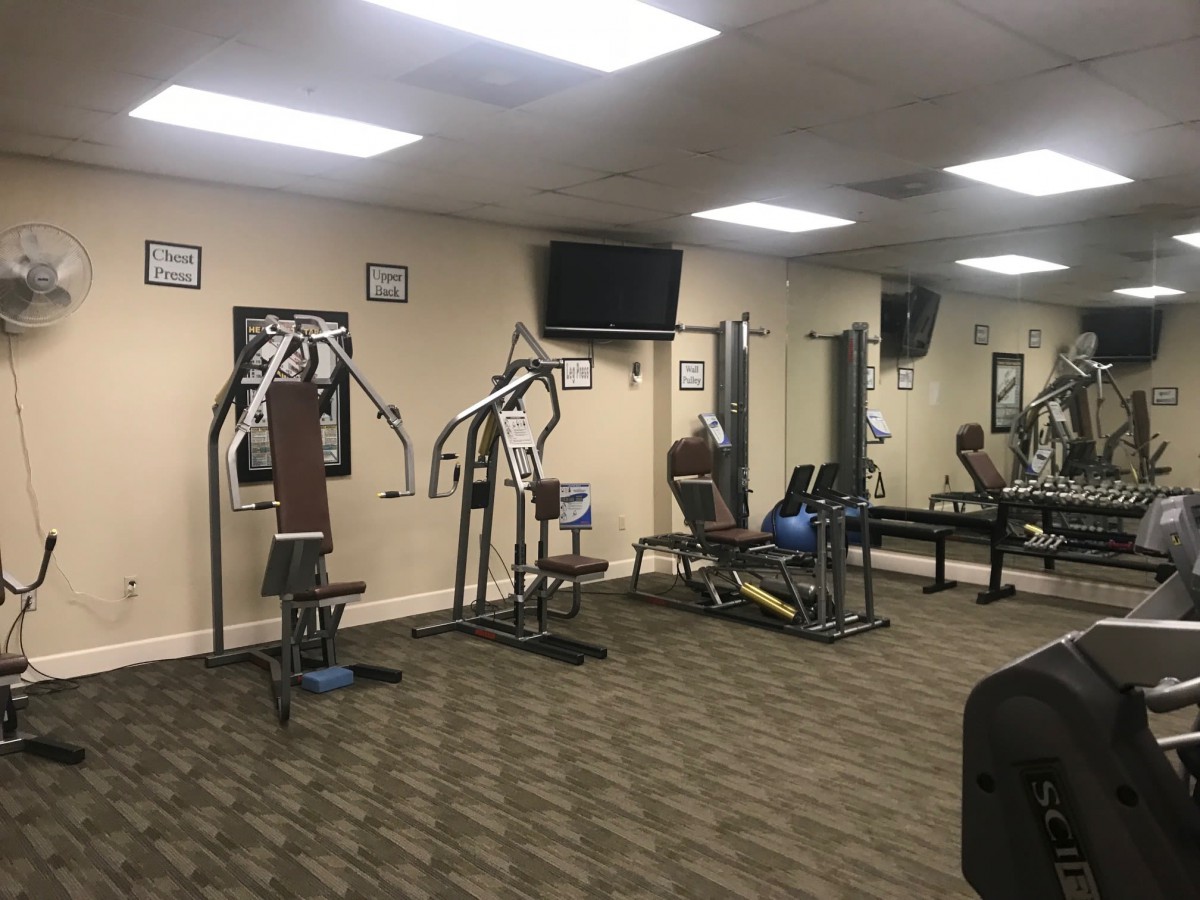 A small gym with various exercise equipment and a wall-mounted TV.
