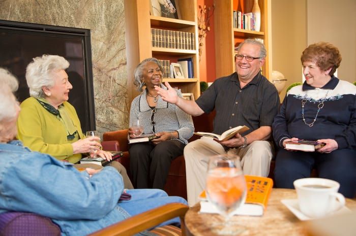 A group of people engaging in a lively book club discussion, surrounded by books and refreshments.