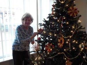 A person decorating a Christmas tree inside a house, capturing the festive holiday spirit.