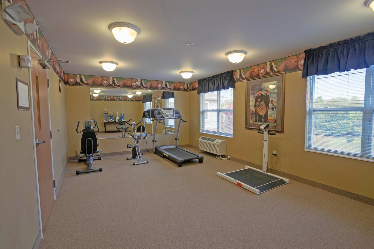 A small indoor gym with exercise equipment including treadmills and weights.
