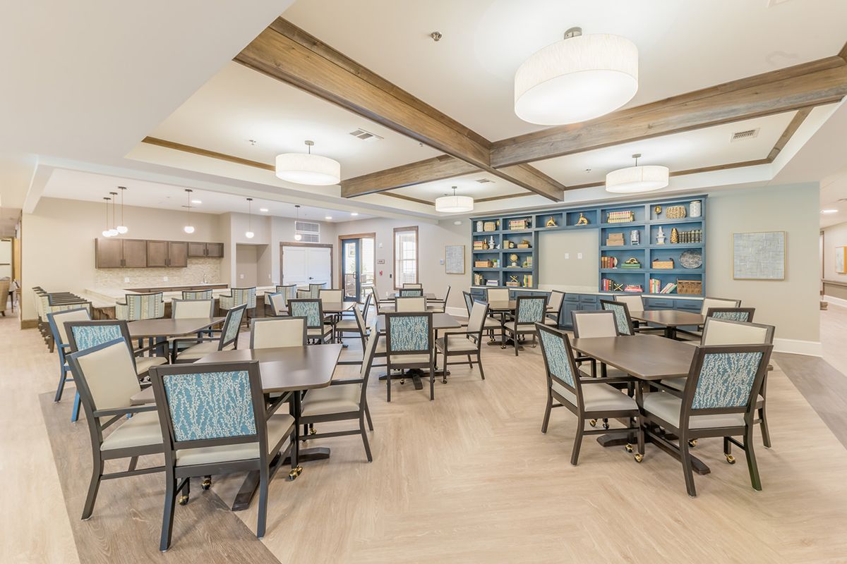 A modern and spacious dining area with neatly arranged tables and chairs, featuring stylish lighting fixtures and contemporary decor.