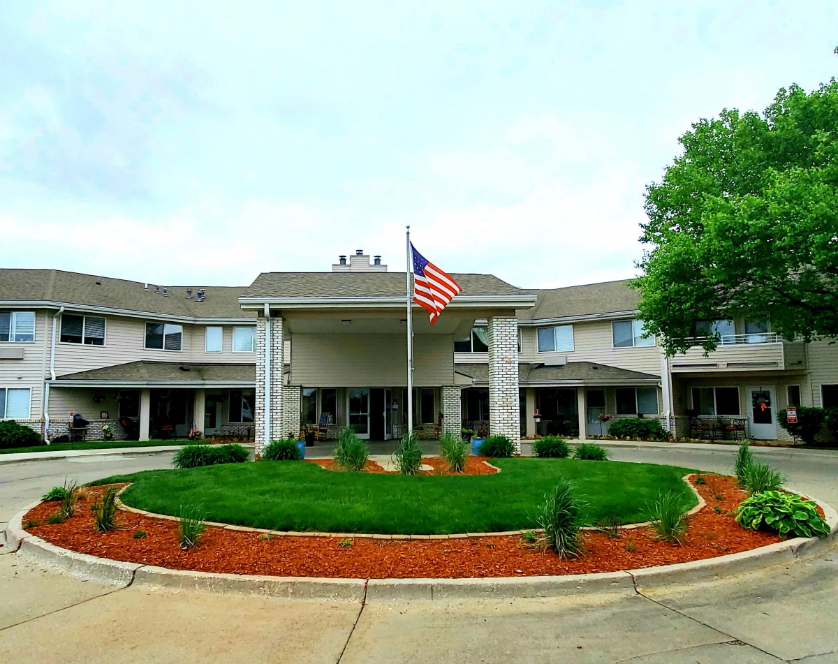 A symmetrical building with a circular driveway and an American flag at the entrance.