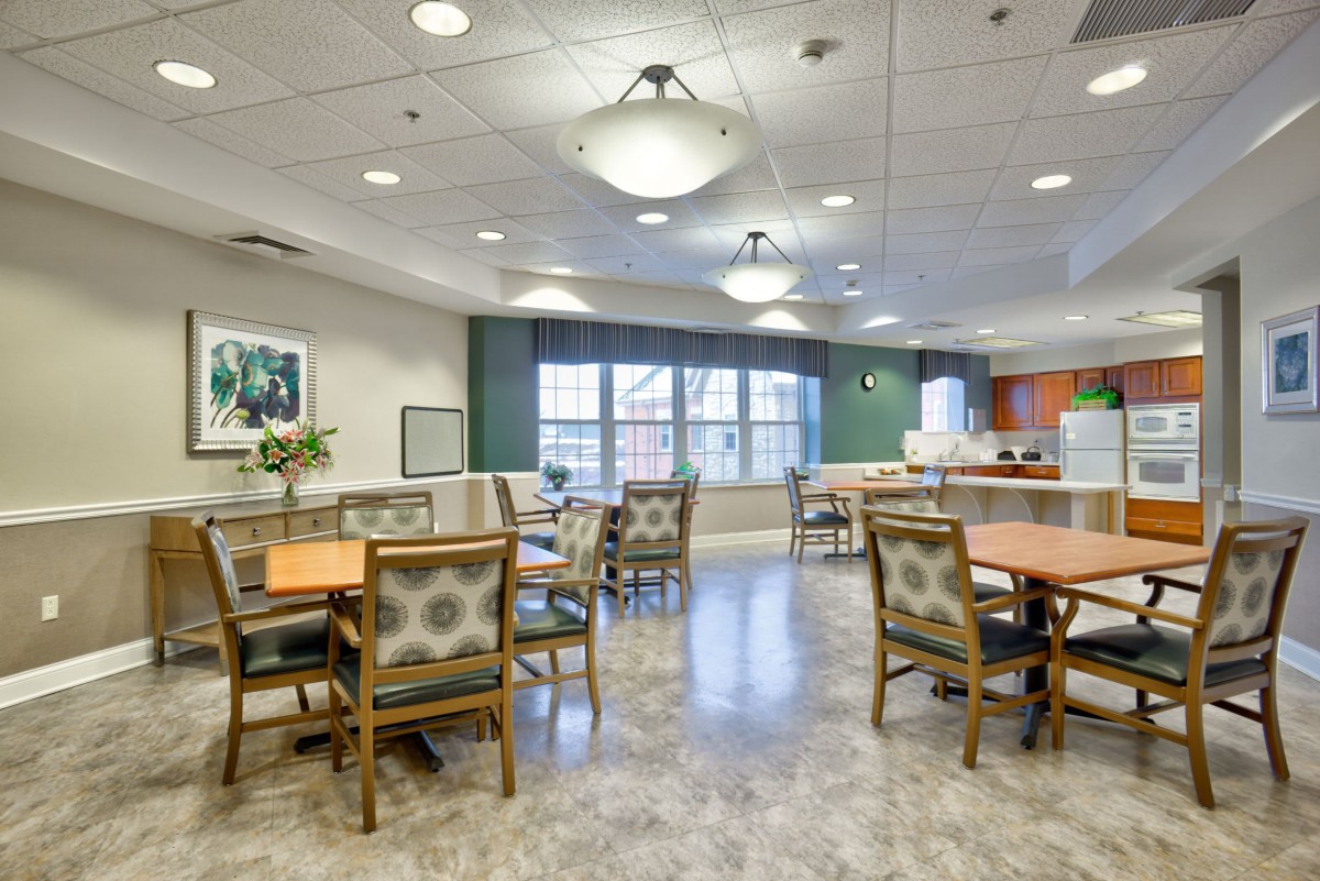 A spacious and well-lit dining area with multiple tables and chairs, featuring large windows.