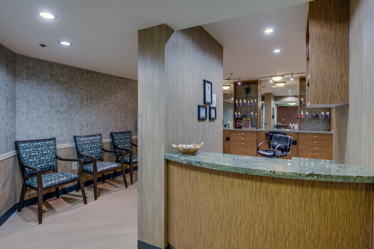 A modern office reception area featuring a counter and waiting chairs.