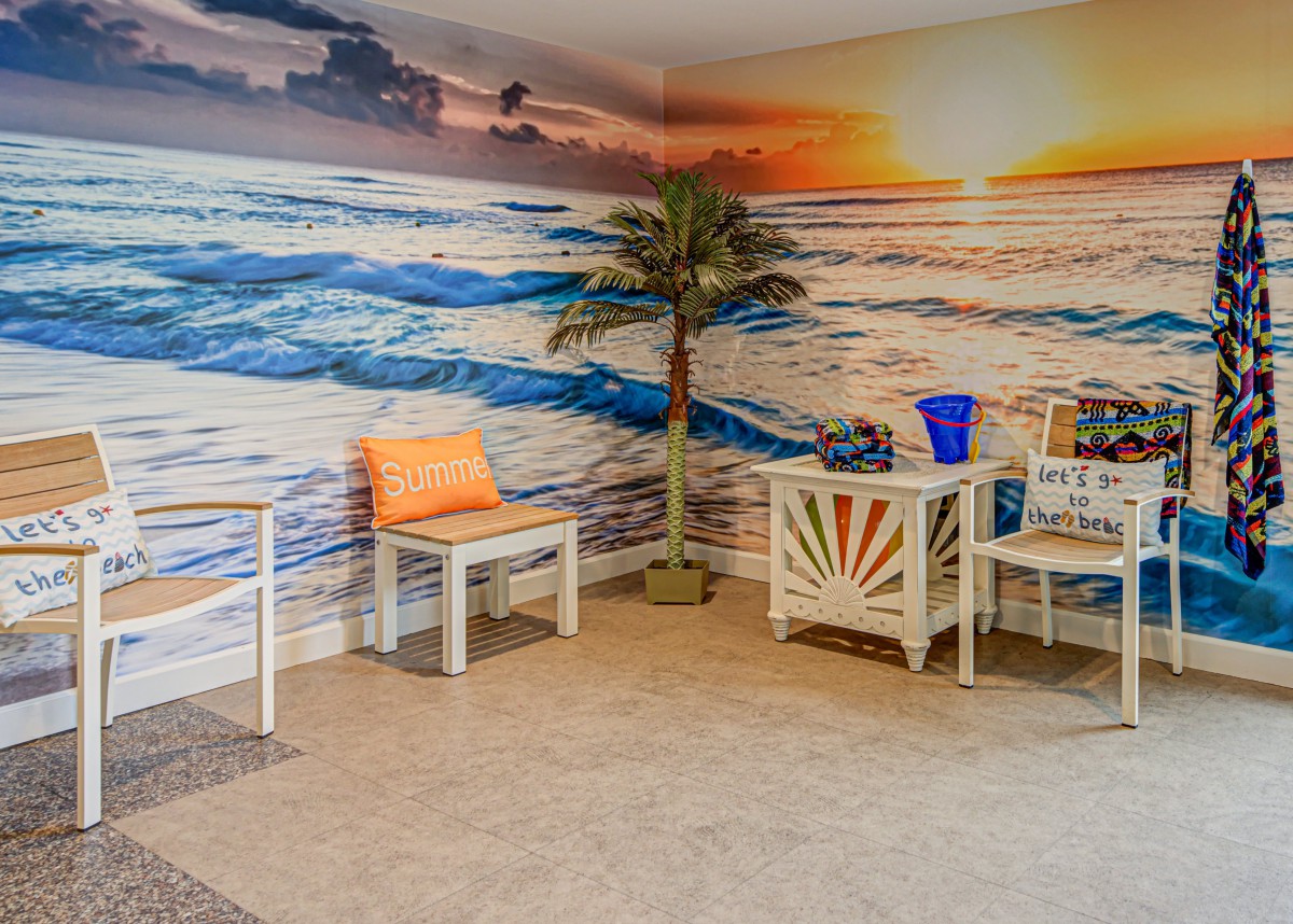 Cozy indoor seating area with a beach-themed mural and tropical decor.