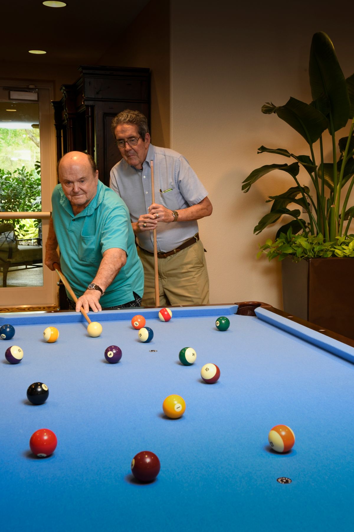 Two men playing billiards indoors, focusing on the game.