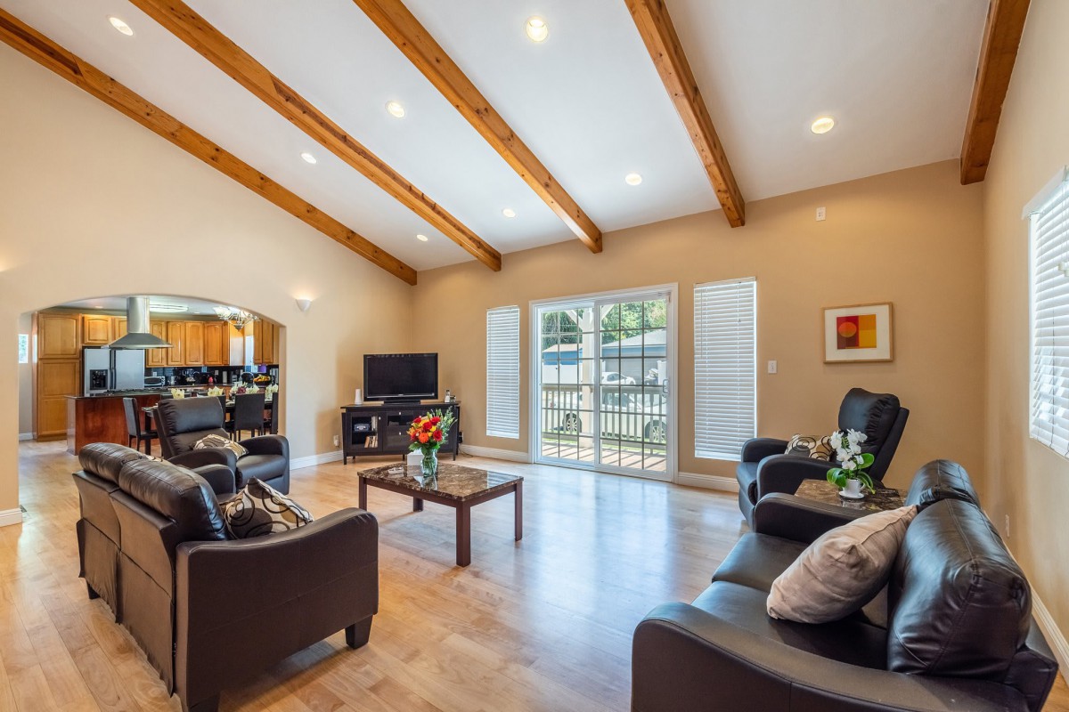 Modern living room with wood beam ceiling, ample natural light, and contemporary furnishings.