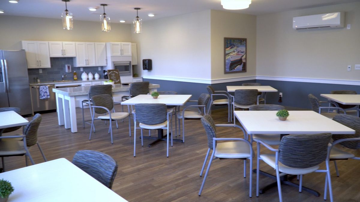A modern dining area with tables and chairs, adjacent to a kitchen space.
