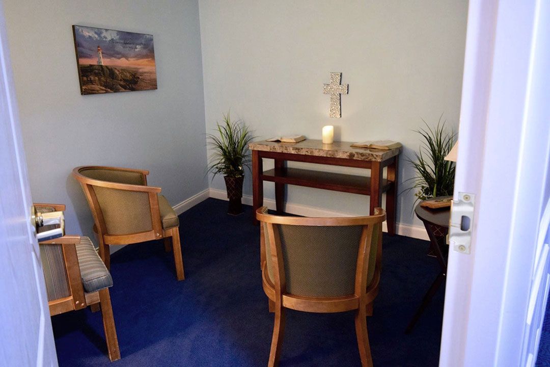 A small chapel with chairs arranged facing an altar adorned with a cross and candle.