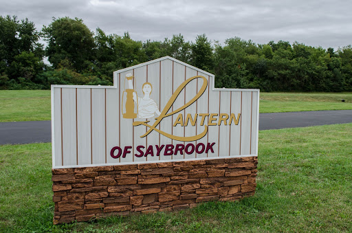 A welcoming sign for the Lantern of Saybrook, set against a green landscape.