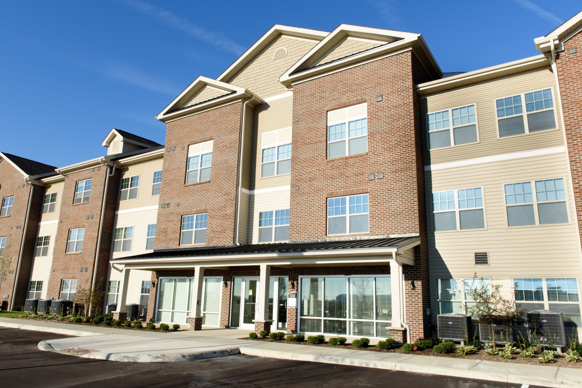A modern brick apartment building with large windows under a clear blue sky.
