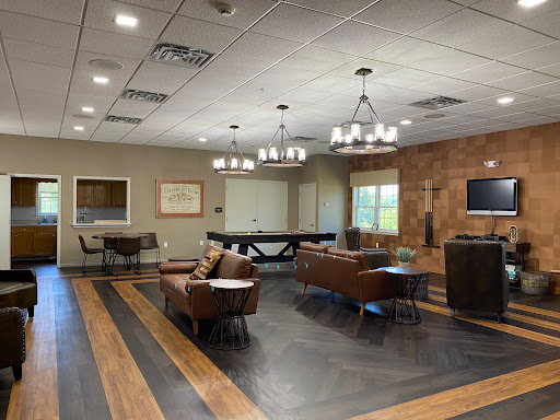 A stylish lounge area featuring comfortable seating, a pool table, and elegant chandeliers.