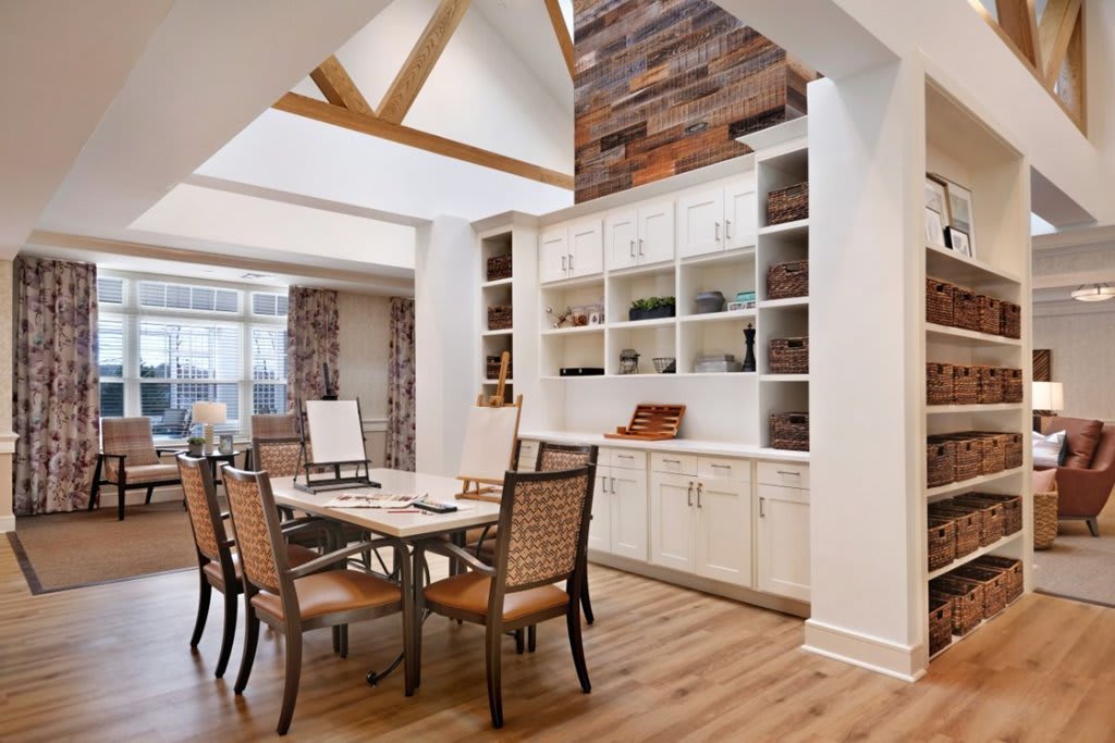 A modern dining room with high ceilings, wooden flooring, and ample natural light.