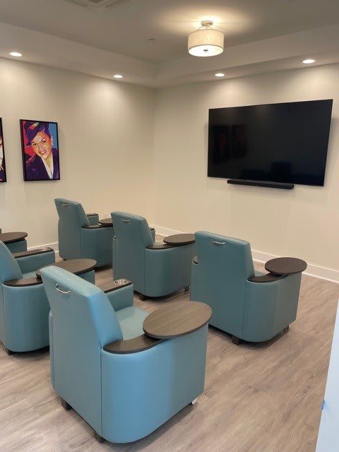 A modern home theater setup with comfy chairs and a large screen, complemented by artwork on the walls.
