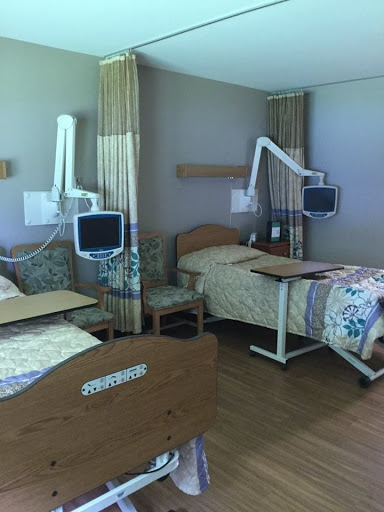 A view of a modern hospital patient room featuring two beds and medical equipment.
