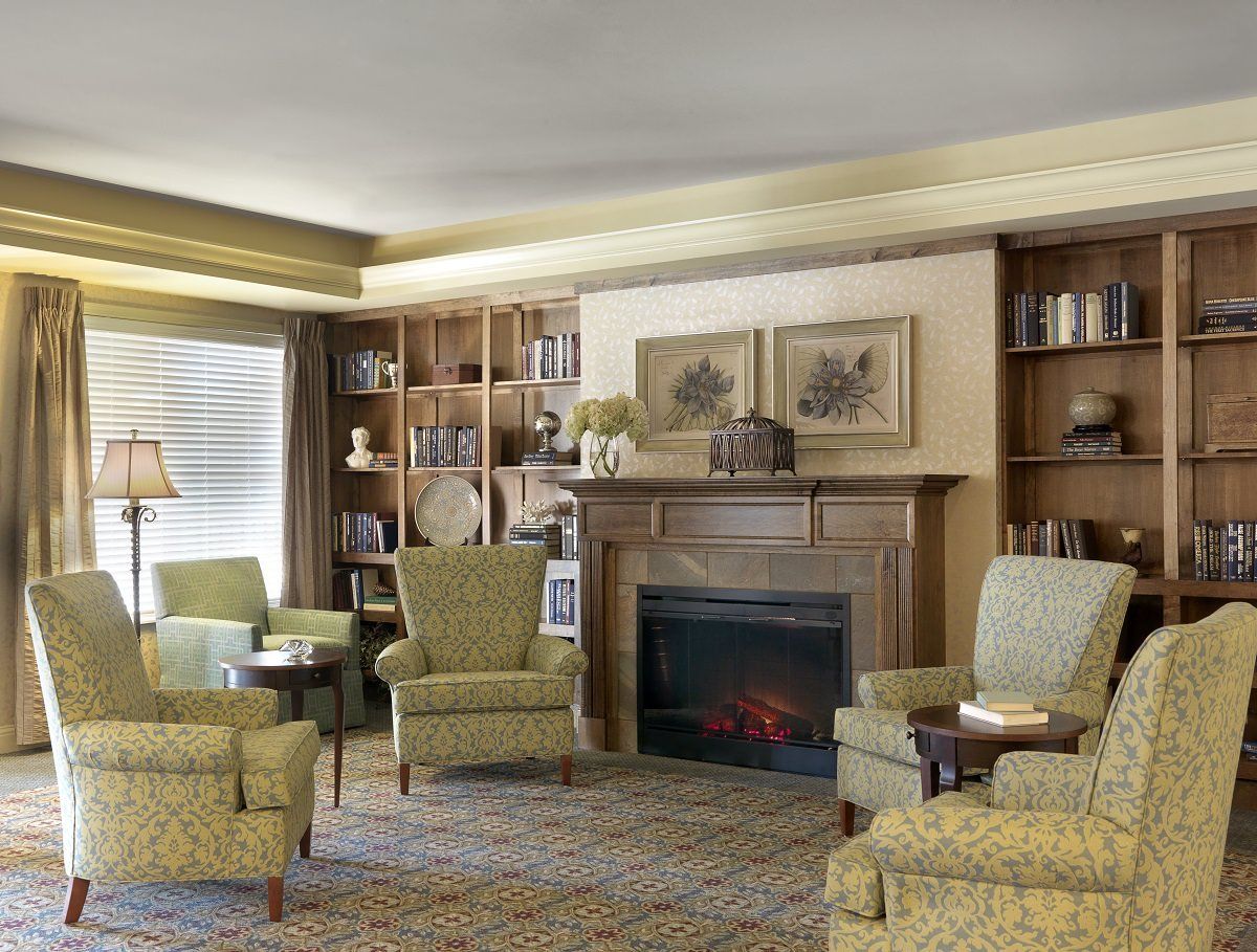 A cozy living room with a fireplace, armchairs, and bookshelves creating a warm atmosphere.