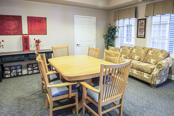 A cozy dining area with a wooden table and matching chairs, complemented by a sofa and decorative elements.