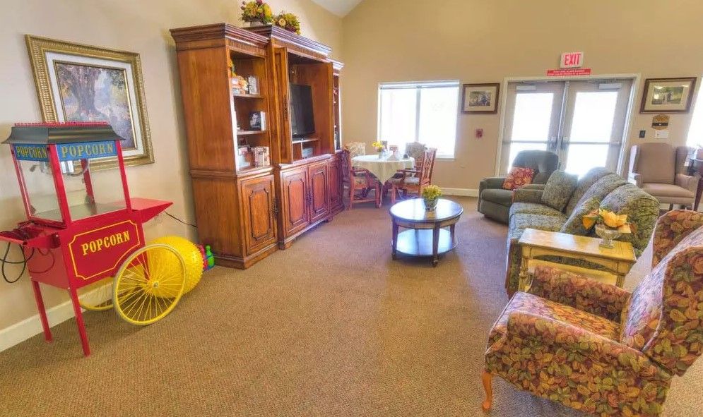 A cozy living room with a large wooden entertainment center, comfortable seating, and natural light from the window.