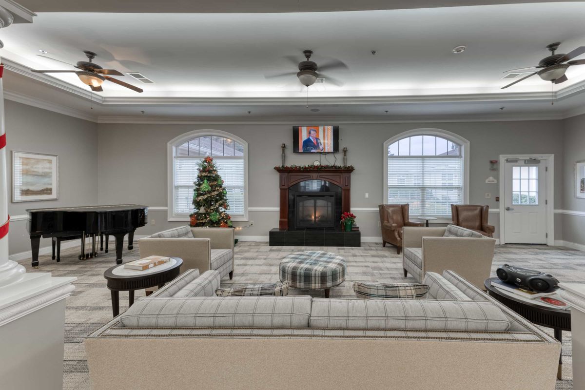 A spacious living room with comfortable seating, a fireplace, and a decorated Christmas tree.