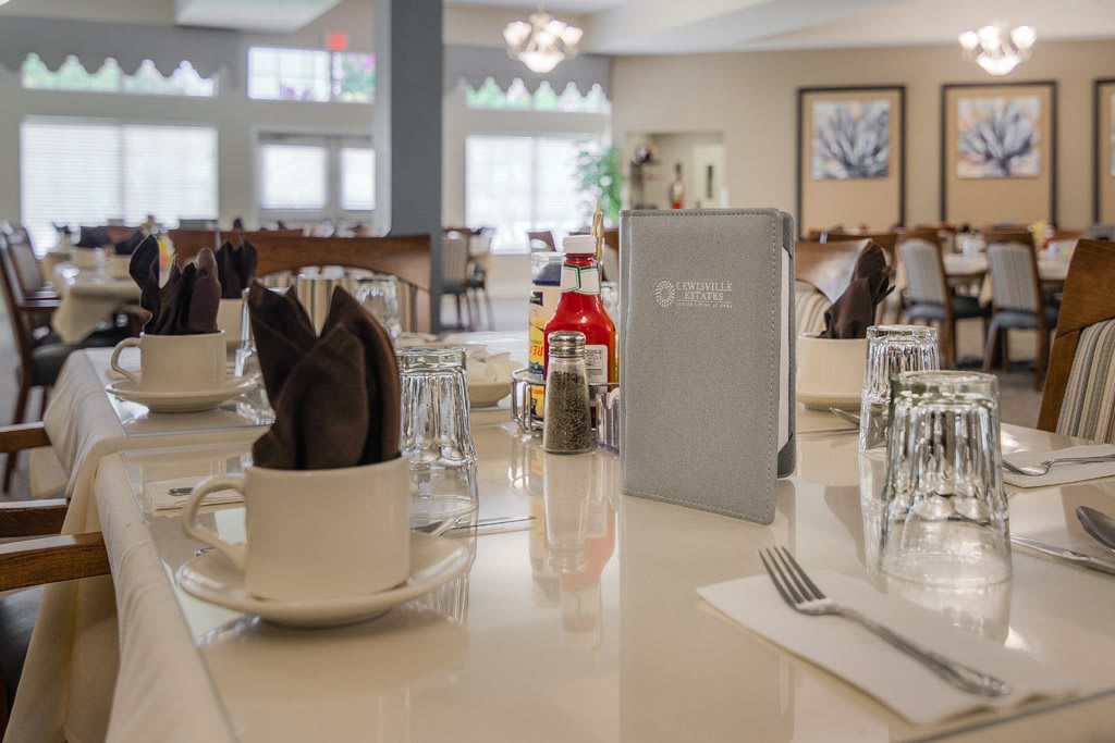 A neatly set table in a restaurant with menus, glasses, and condiments.
