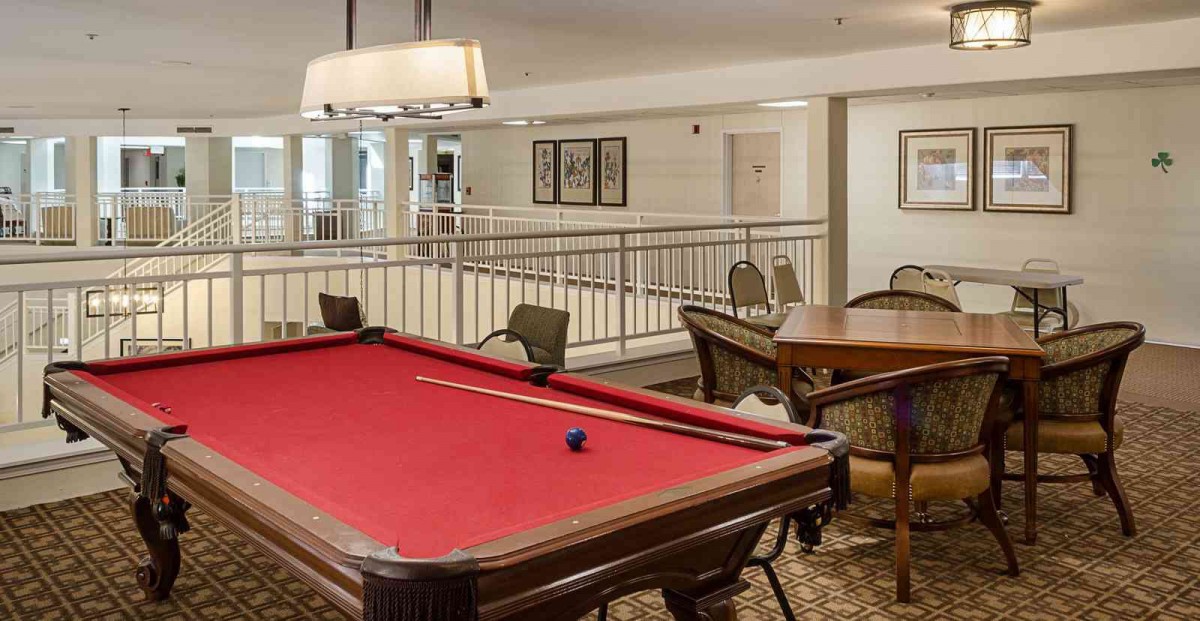 A recreation room featuring a red pool table and seating area.
