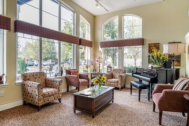 A cozy living room with comfortable seating, a piano, and large windows allowing ample natural light.