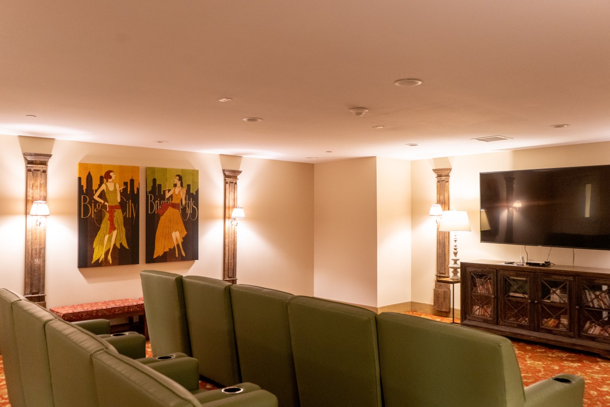 A cozy home theater with green seating, wall art, and ambient lighting.