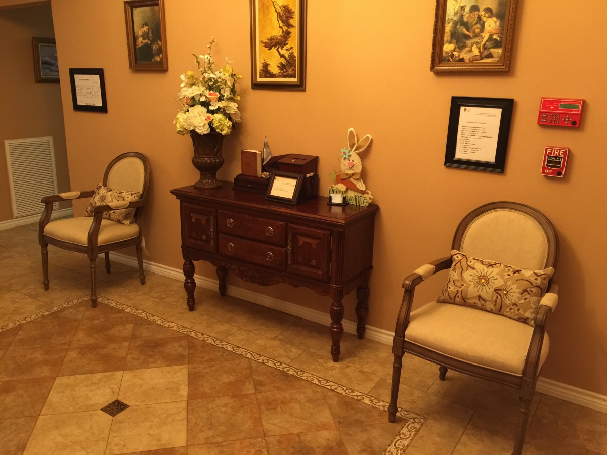 A cozy waiting room with elegant chairs, a decorative table, and warm lighting.